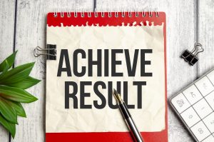 Achieve result text on white notebook and pen on wooden background